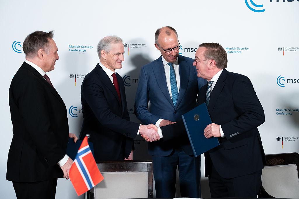 Líderes europeus apertam as mãos durante reunião oficial na Conferência de Segurança de Munique 2026, reforçando cooperação em matéria de defesa.