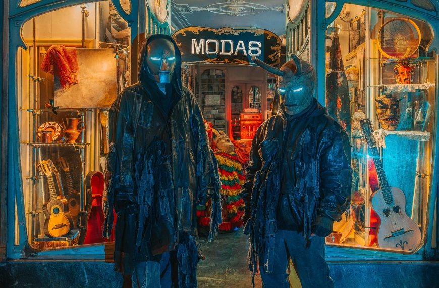 Karetus à porta de uma retrosaria tradicional com máscaras e instrumentos portugueses, numa estética futurista ligada ao álbum “MODAS”.