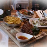 Bife grelhado servido com batatas fritas, legumes e molho num restaurante em Portugal