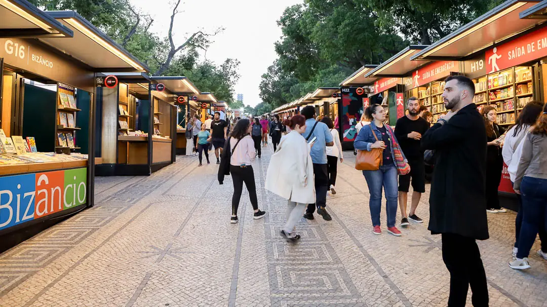 Feira do Livro de Lisboa com pavilhões de livros e visitantes a caminhar