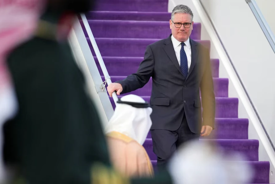 Keir Starmer desce escadas em chegada oficial durante contexto de crise internacional com o Irão