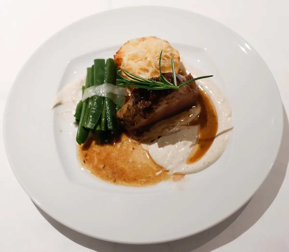 Prato de carne com feijão verde e molho cremoso em restaurante fine dining em Portugal