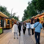 Visitantes na Feira do Livro de Lisboa 2026 no Parque Eduardo VII entre pavilhões de editoras e livrarias.