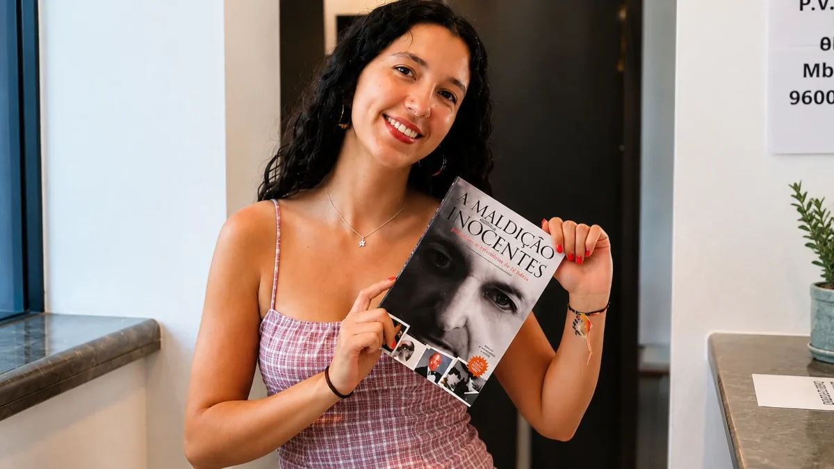 Jovem participante segura o livro A Maldição dos Inocentes durante sessão de apresentação da obra.