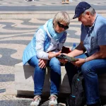 Casal de turistas consulta um mapa e um telemóvel na Praça D. Pedro IV, no Rossio, em Lisboa.