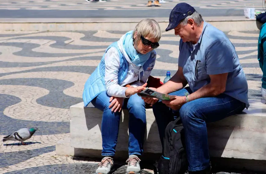 Casal de turistas consulta um mapa e um telemóvel na Praça D. Pedro IV, no Rossio, em Lisboa.