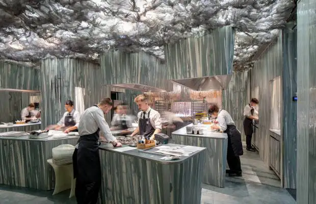 Interior do restaurante Enigma, em Barcelona, com a cozinha aberta e a equipa liderada por Albert Adrià a preparar o menu de degustação.