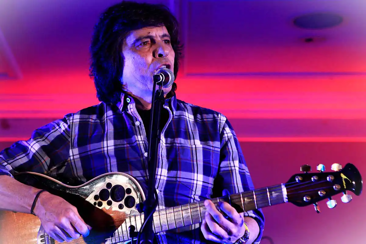 Luís Represas atua em palco durante um concerto, numa imagem que homenageia a voz histórica dos Trovante e da música portuguesa.